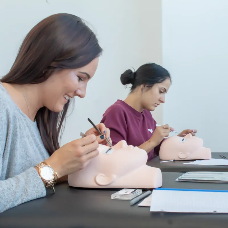 Students practising lash application on mannequin heads